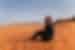 Smiling traveller sitting on sand dune in desert of Wadi Rum, Jordan