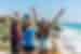 Travellers throw their hands up for a group photo looking out at the ocean in Tulum, Mexicoa