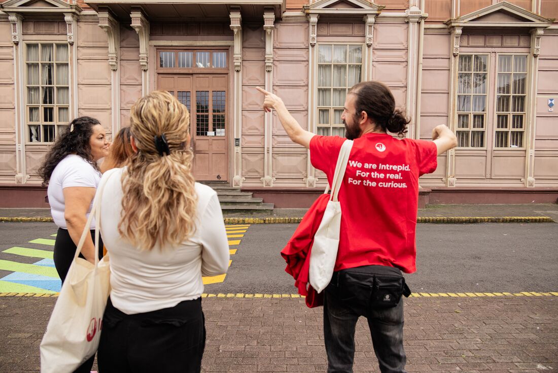 Leader pointing at University while talking to travellers on a walk in the town centre of San Jose, Costa Rica