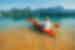 Mother and son push from shore to go kayaking on Cheow Lan Lake in Khao Sok National Park in summer